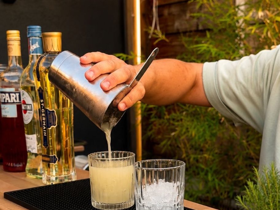 Barman du Hope versant un cocktail du shaker dans un verre, en gros plan